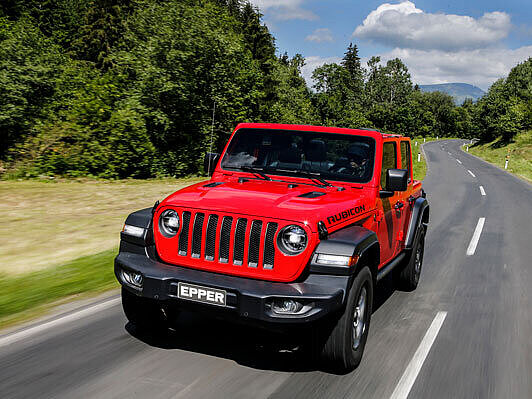 Der neue Jeep Wrangler auf einer Landstrasse mit einem Wald im Hintergrund