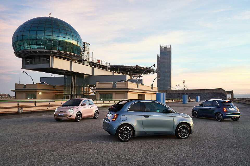 Mehrere Fiats, die auf einem Parkplatz stehen.