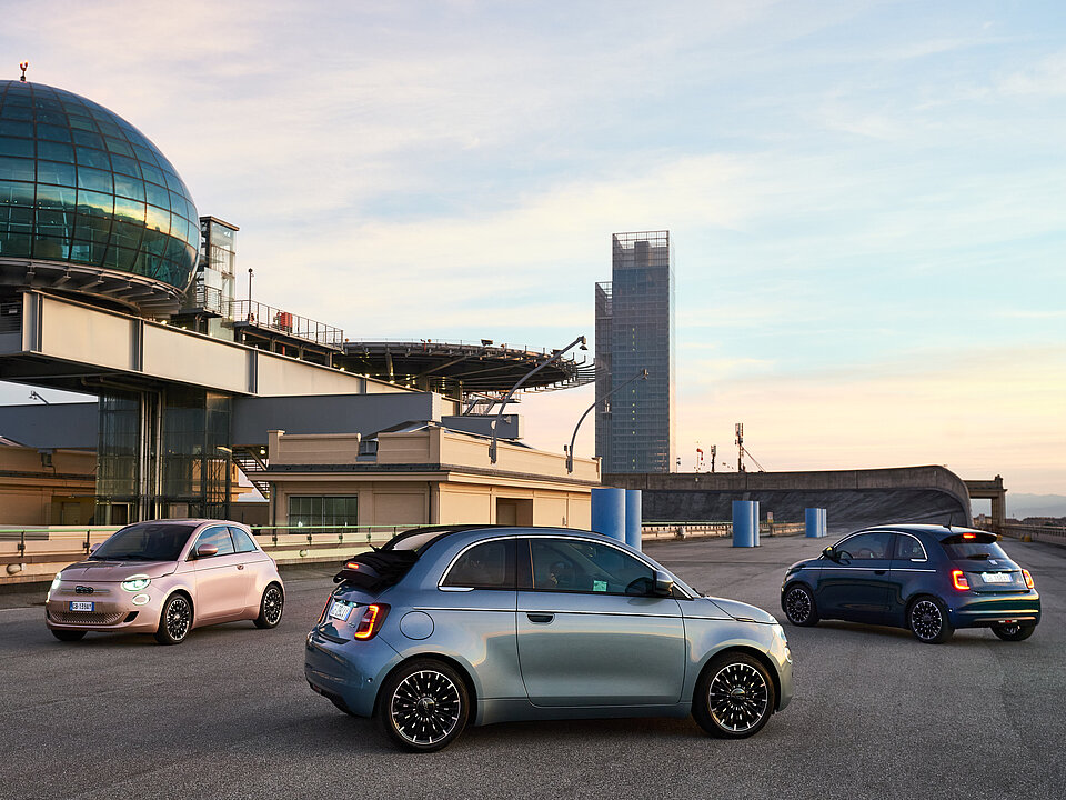 Mehrere Fiats, die auf einem Parkplatz stehen.