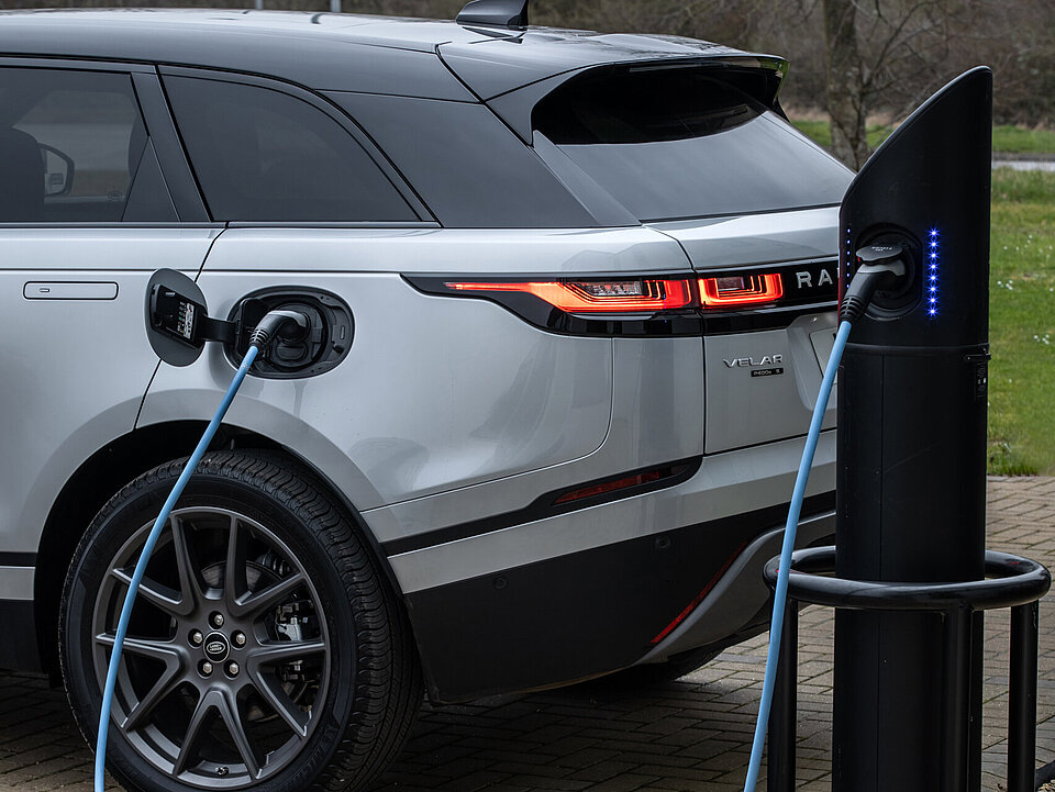 Land Rover Velar beim laden vor einer Wiese
