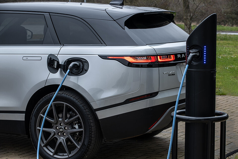 Land Rover Velar beim laden vor einer Wiese
