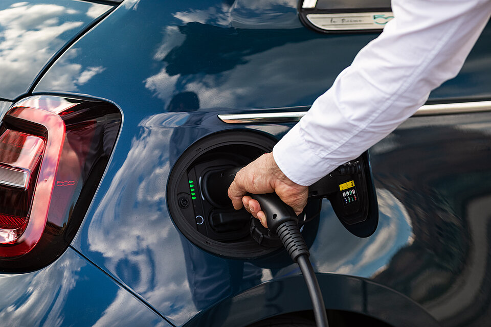 Ein Mann lädt den blauen elektrischen Fiat.