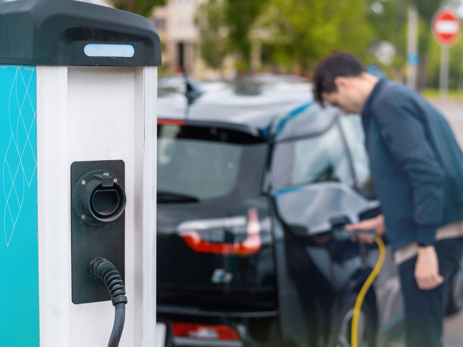 Ein Mann steckt sein Auto an einer öffentlichen Ladestation ein.