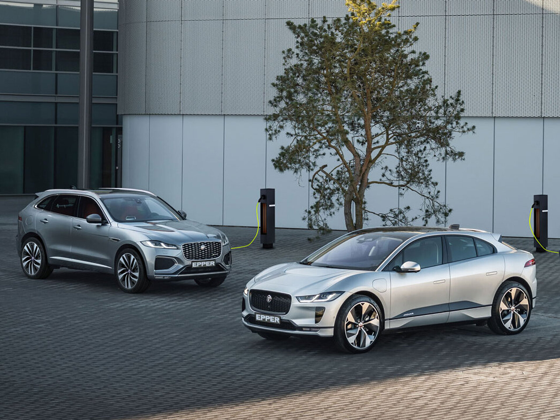 Ein vollelektrischer und zwei Plug-In Hybrid Jaguar auf einem Platz am laden