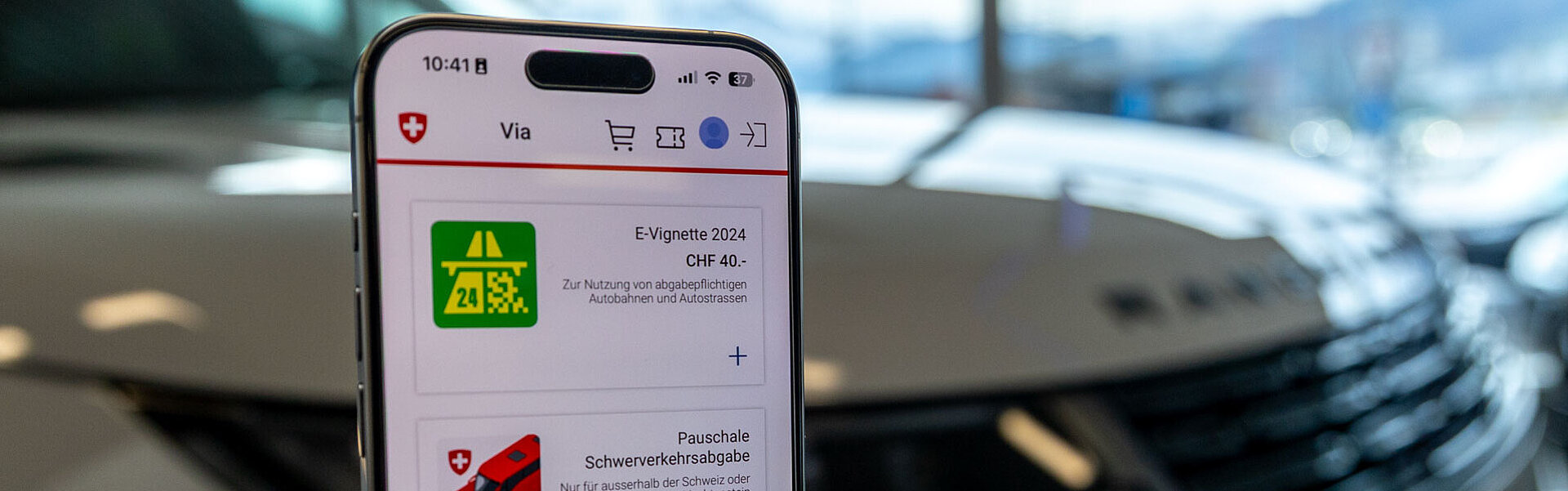 Ein Smartphone mit der E-Vignette vor einem Fahrzeug