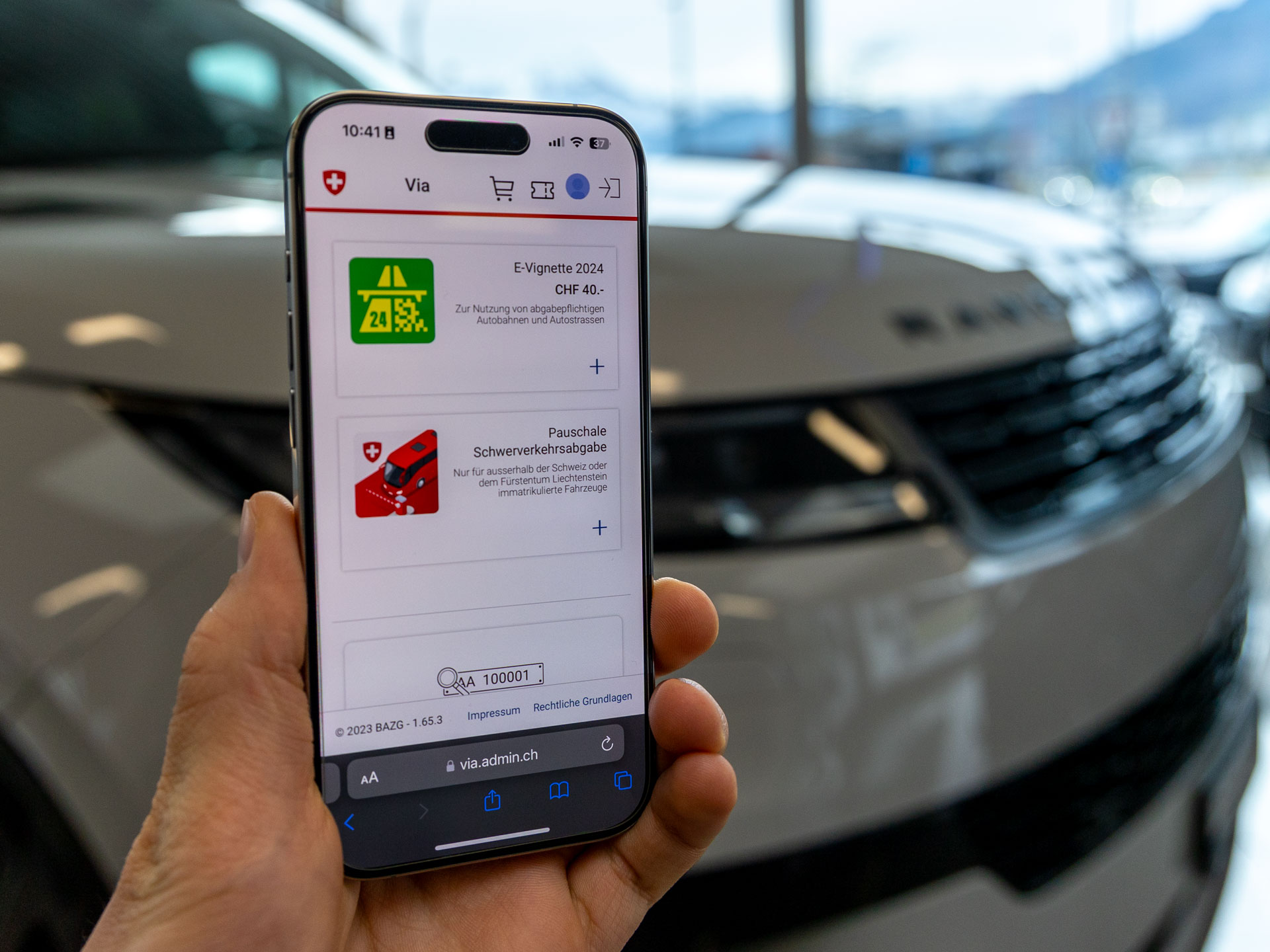Smartphone mit E-Vignette vor dem Fahrzeug